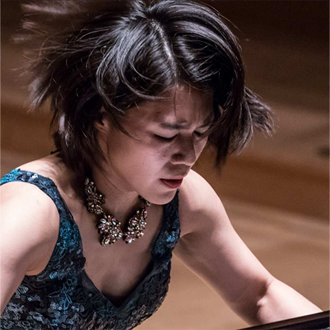 Charlotte Hu playing piano; close up on her face, which has a serious, focused expression..