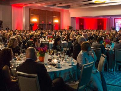 Interior of event venue with people in formal attire seated at round tables