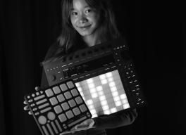 Bethanie Liu holding a series of electronic digital instruments and samplers