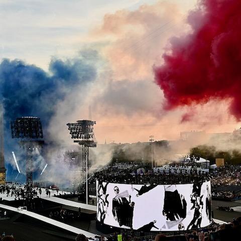 Aerial shot of the 2024 Paralympics opening ceremony featuring a stage of performers and a plume of smoke in the colors of the French flag