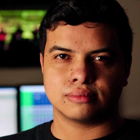 Headshot of Mateo Londoño with a music production setup in the background