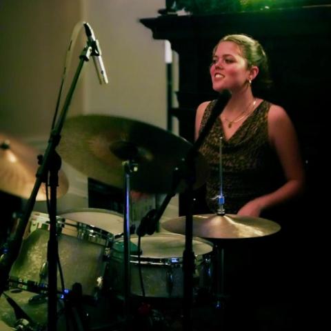 Flora Sullivan sitting behind a drum kit during a performance