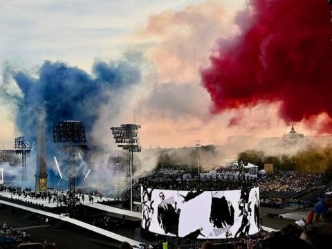 Aerial shot of the 2024 Paralympics opening ceremony featuring a stage of performers and a plume of smoke in the colors of the French flag